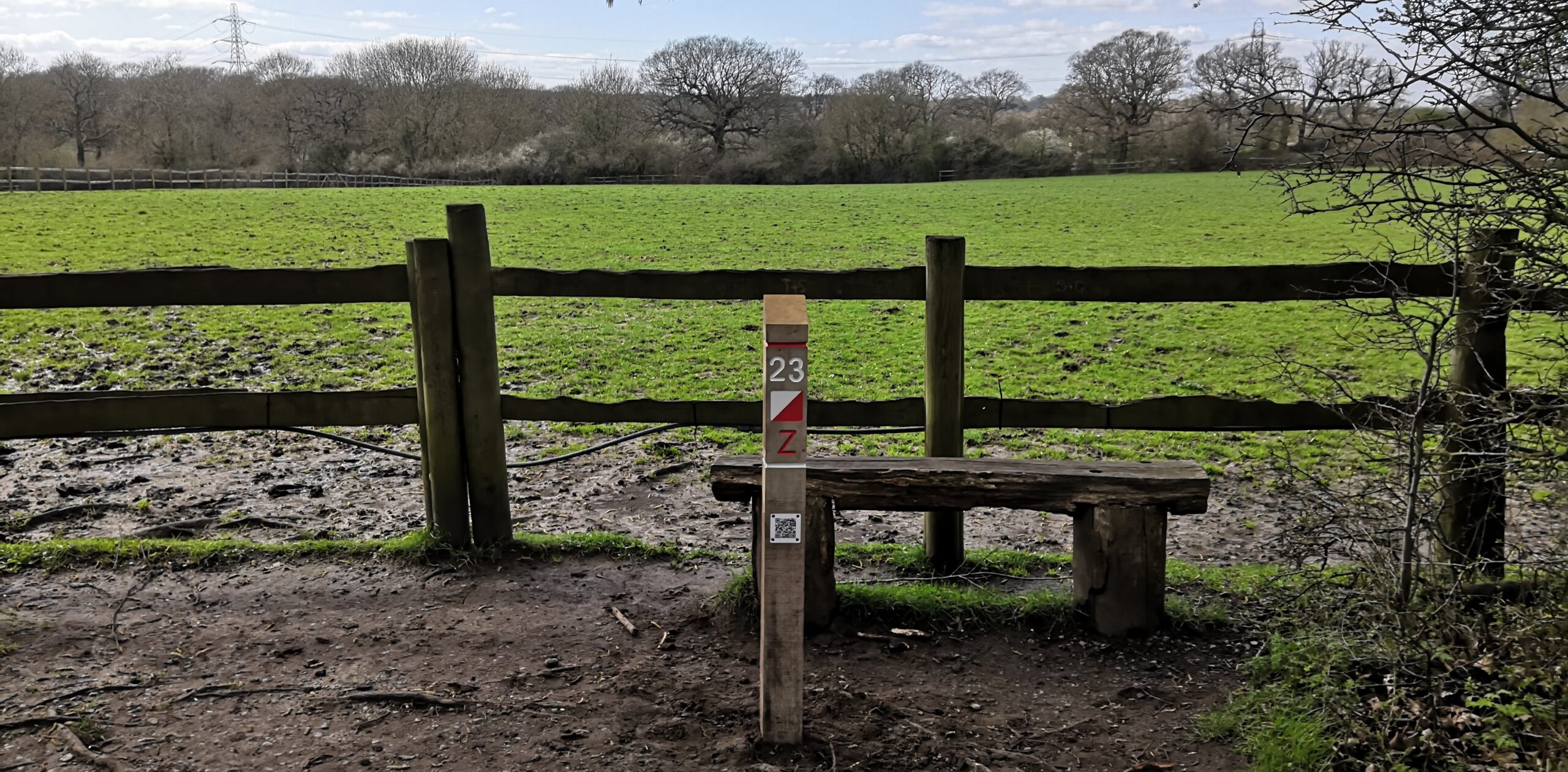 An example of a control (by a bench, beside a fenced field) from a permanent orienteering course.